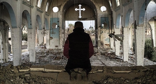 térdelő férfi egy lerombolt templomban