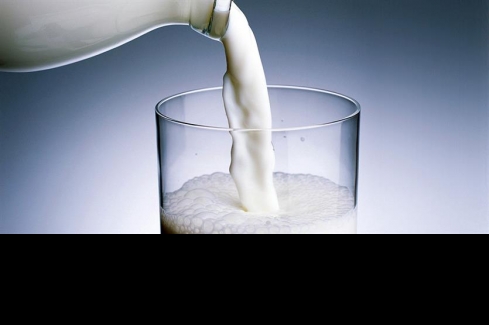 üvegből pohárba ömlő tej