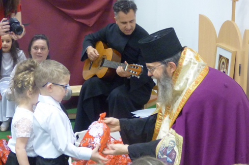 Atanáz püspök ajándékot ad át az óvodában, a háttrében Janka Gábor atya